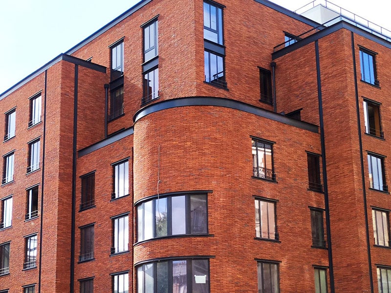 Image de la façade d'un bâtiment en brique rouge au coin d'une rue