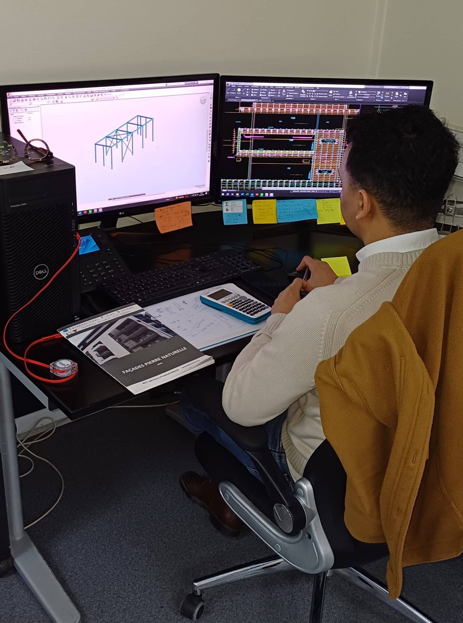 Image de présentation d'un homme assis à un bureau avec deux écrans d'ordinateur en train de travailler.